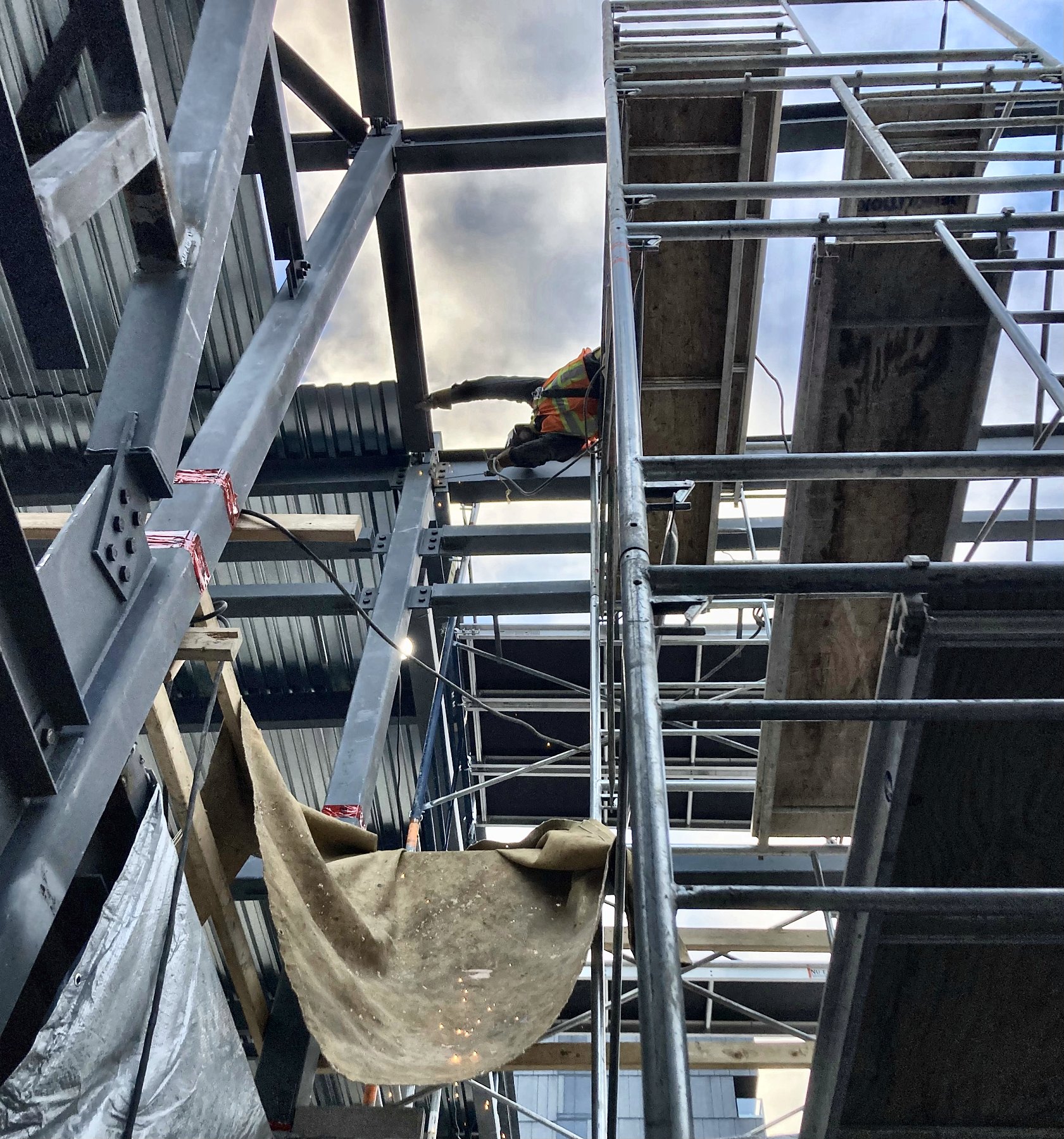 Weld Plus welder working on roof deck framing from a scaffold