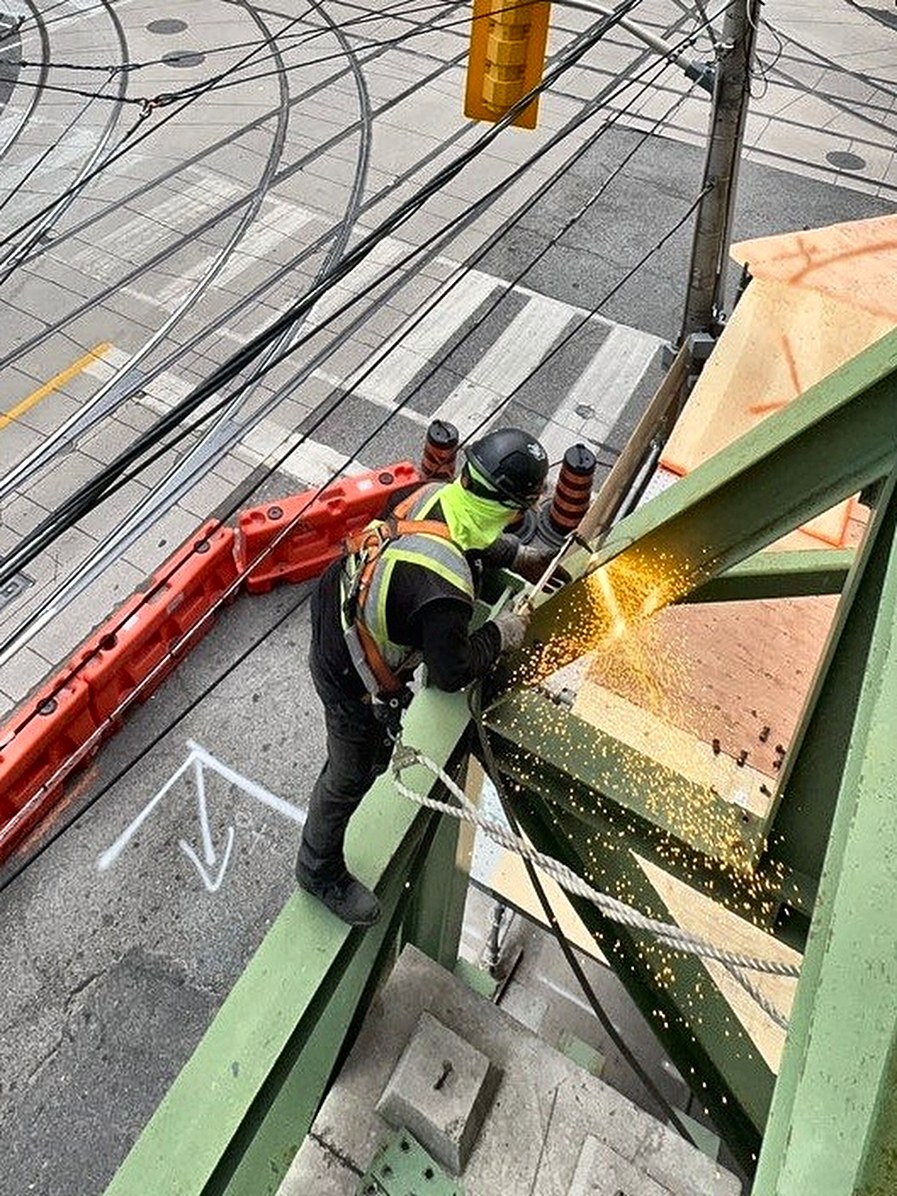 Weld Plus welder cutting a structural steel retention frame above a downtown Toronto street