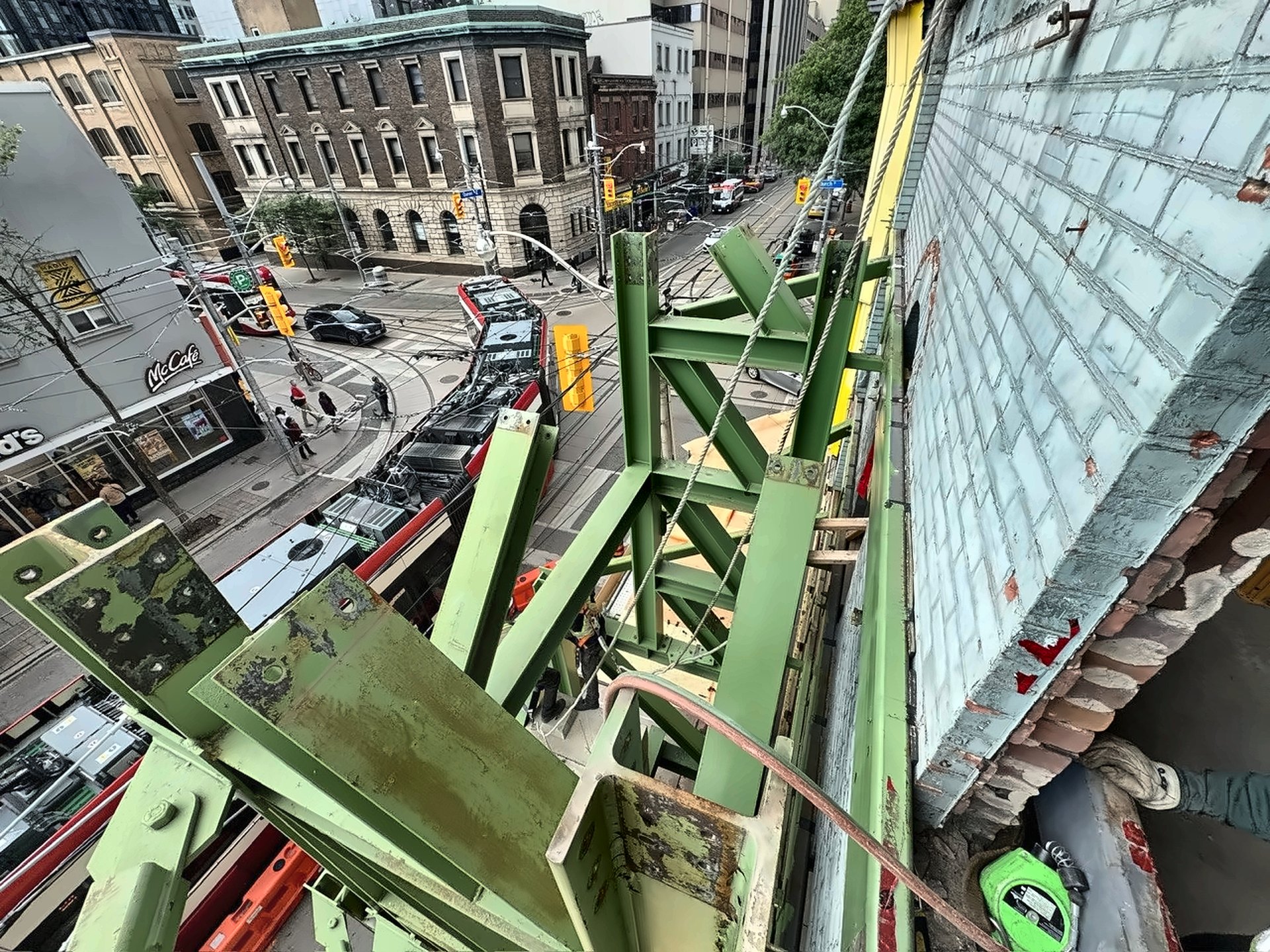 Heritage masonry facade retained by a temporary structural steel frame above a downtown Toronto streetcar corridor