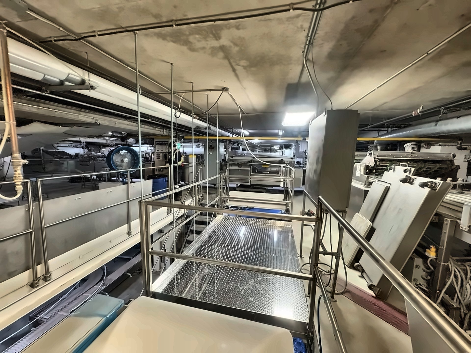 Elevated mezzanine walkway extension with diamond plate decking above conveyor machinery, GTA industrial facility